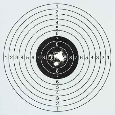 Gun shots at a paper gun target with a high score in the middle. Concept image about hitting the target, well out in range, business goals, success, accuracy etc.
